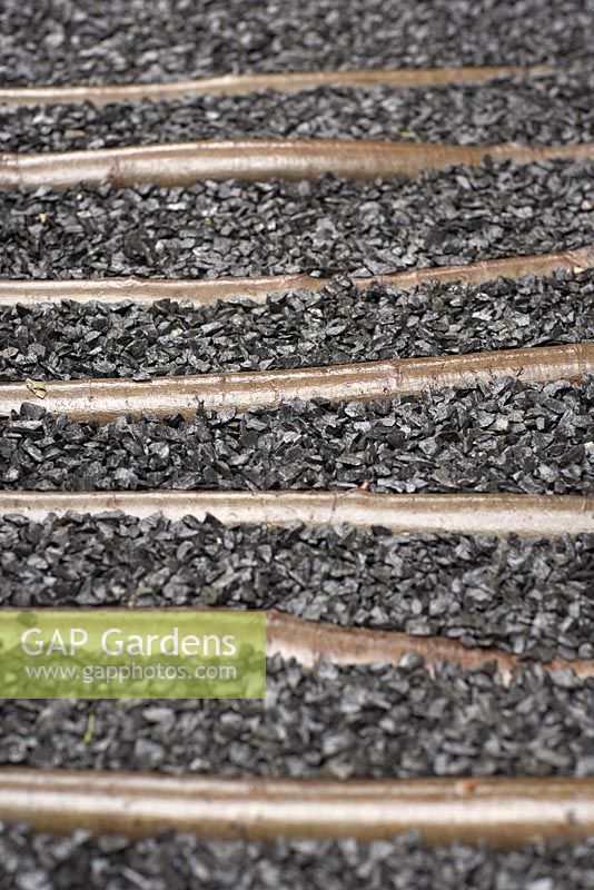 Detail of grey gravel and inlaid branch pathway.   The Hidden Beauty of  Kranji by Esmond Landscape and Uniseal.  RHS Chelsea Flower Show 2015
