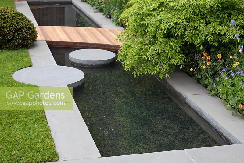 The Homebase Urban Retreat Garden. Detail of wooden decking leading across water feature.