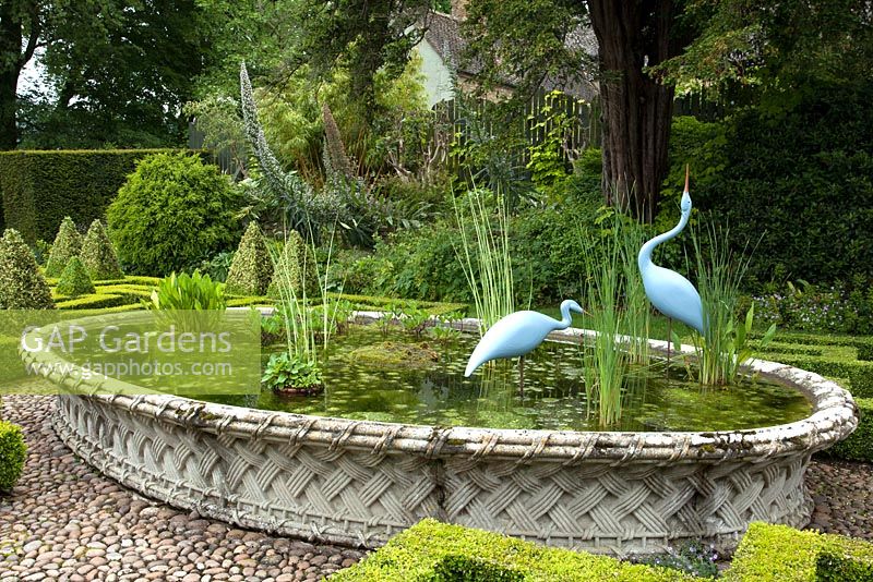 Basket Pond from the Great Exhibition of 1851 with Two Herons by Michael Lythgoe in the Knot Garden, Bourton House, Bourton-on-the-Hill, Moreton-in-Marsh, Gloucestershire, UK.