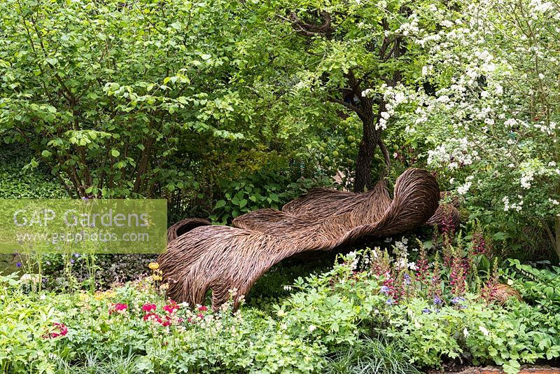 Woven willow seat in a tranquil woodland glade. Breast Cancer Haven Garden. RHS Chelsea Flower Show, 2015