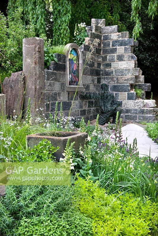 Stone walled church ruin, pathway, water trough and cottage garden plants including Digitalis purpurea - foxglove and herbs. The Evaders Garden by Chorley Council. RHS Chelsea Flower Show, 2015.