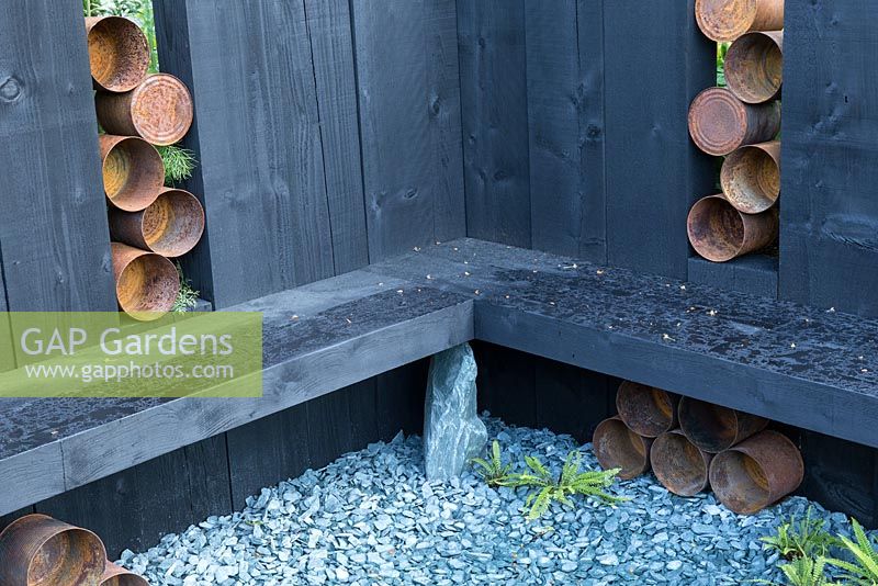 The Great Chelsea Garden Challenge - old rusty tin cans and wooden bench in slate gravel seating area 