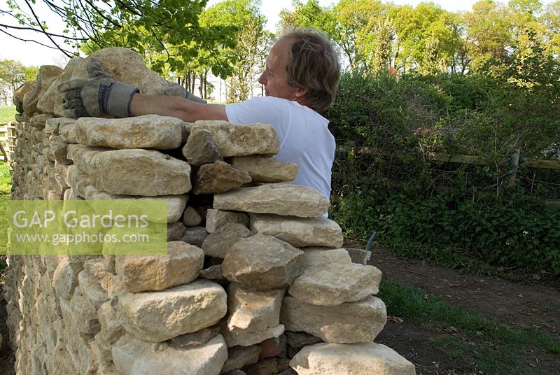Placing the top stones, edge on, on the wall.