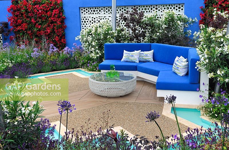 Mediterranean style garden with central pool and fountain, turquoise rills, built-in bench with blue cushions, white aluminium panels set in blue painted walls with sections of flowering bougainvillea - Noble Caledonia: Spirit of the Aegean, RHS Hampton Court Palace Flower Show 2015