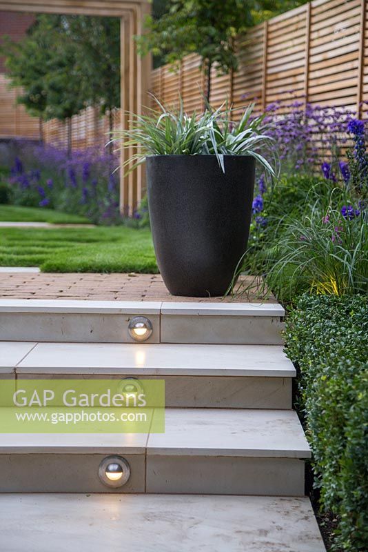 Lighting feature built into the marble steps, with potted Astelia chathamica and view to Verbena bonariensis border