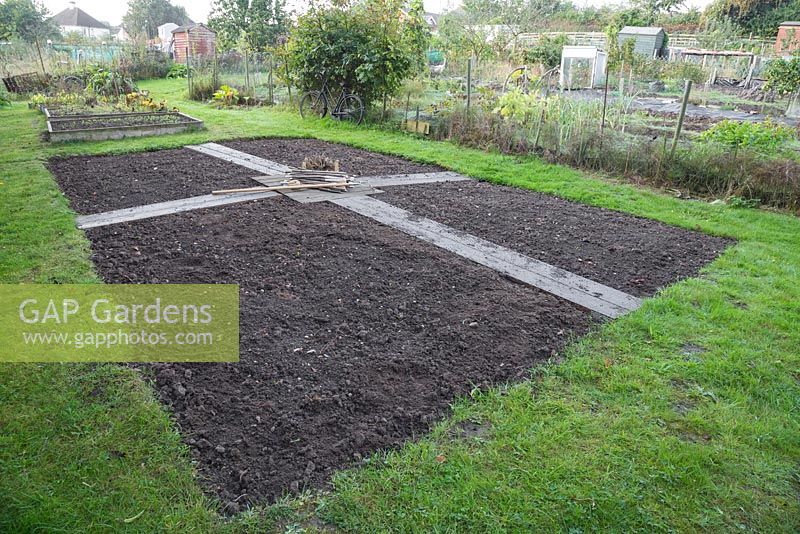 A large section of an Allotment plot allocated for a cutting garden. Materials required are Hazel stick plant labels, string, rake, tubers, bulbs and seeds.