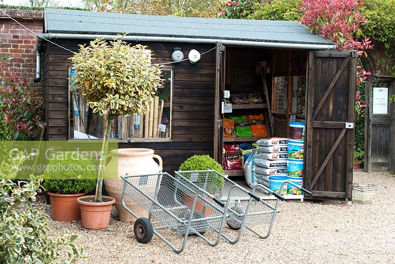 Sales shed with compost bags, Buxus - box balls and trolleys at The Place For Plants, Suffolk