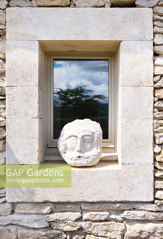 Stone head in pool house window.  Wasserman Garden, Luberon, France. 