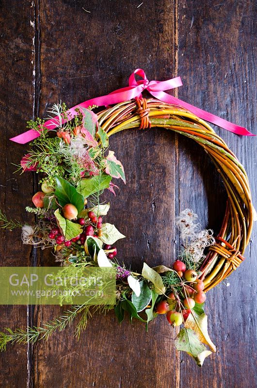 Handmade willow wreath using hedgerow fruits and foliage, decorated wth a pink ribbon - Common Farm Flowers, Somerset