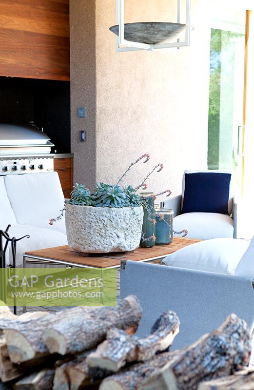 View of covered seating area in kitchen by the pool, with Echeveria in modern container.