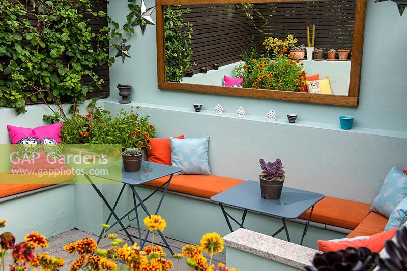An outdoor room with built in benches between raised beds planted with Gaillardia.