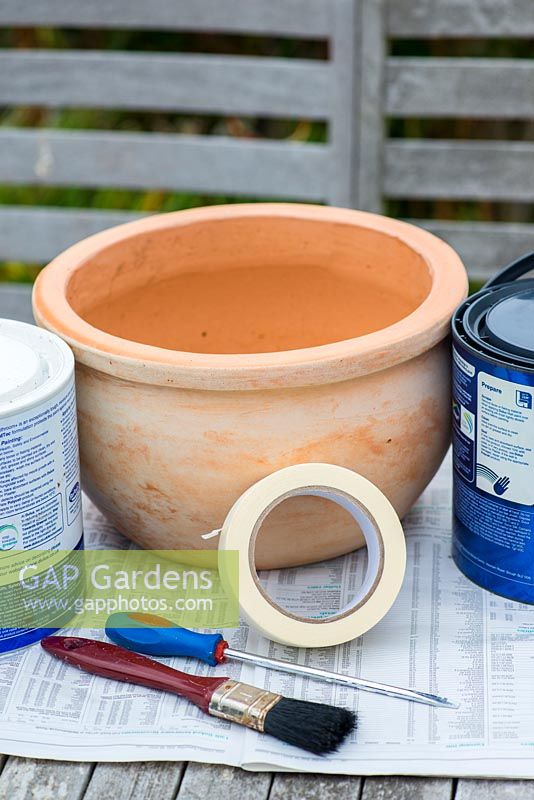Painting a seaside themed container step by step. Step 1: You will need a porous terracotta pot, two contrasting colours of bathroom paint and masking tape.