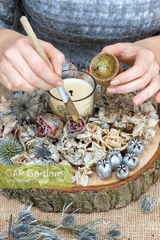 Creating a festive table decoration with garden flowers and seed heads. Paint rose buds with gold glitter.