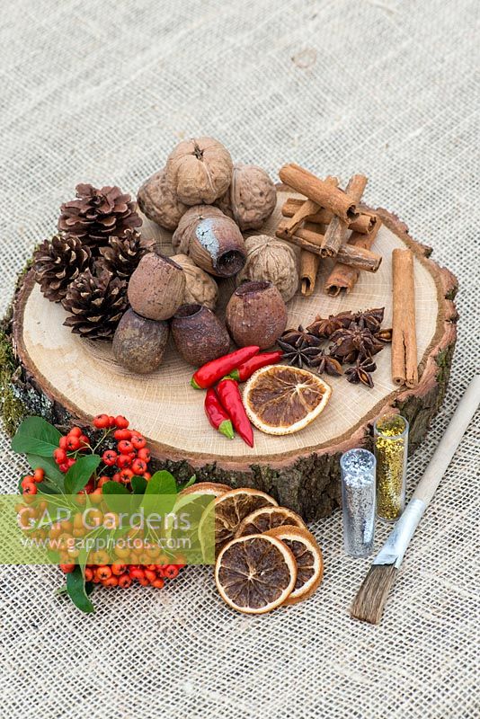 Creating a festive table decoration with dried fruit, nuts, seeds, with freshly picked berries and chilli peppers. Prepare with oak base, glue and glitter.