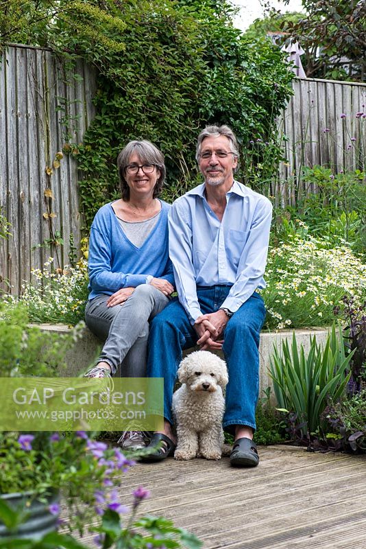 Laura Wahburn Hutton, cookery writer, and Ian Pollock in their London garden with Ted, a bichon frise dog.