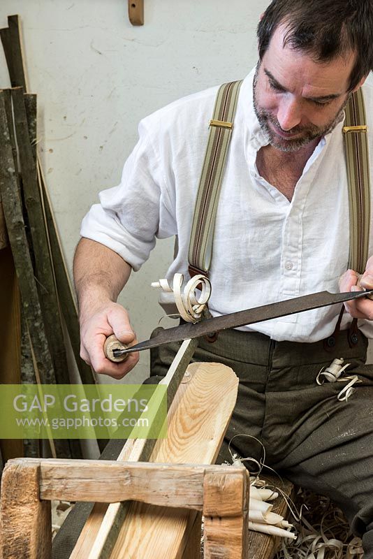 Charlie Groves making a traditional Sussex trug. Using a drawknife to shave a long length of coppiced sweet chesnut. This will form the rim and handle of the trug.