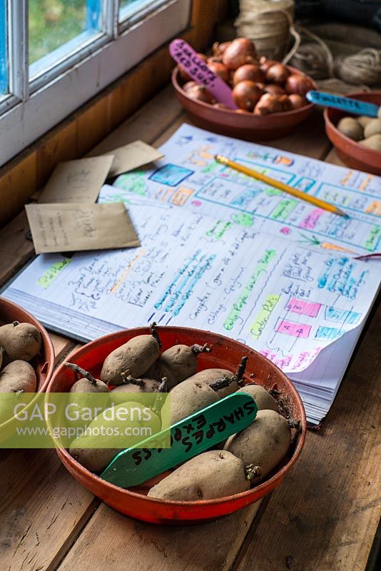 Potting bench showing garden planner with handwritten highlighted diagrams and notes for the growing season.