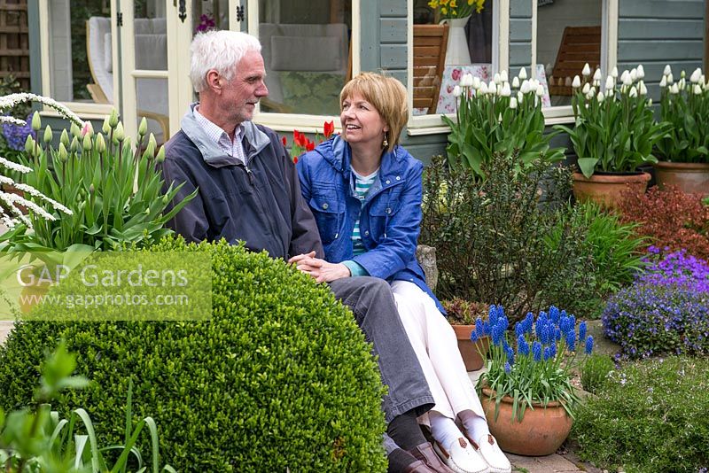 Tony and Julie Peckham in their late spring garden, sitting on the steps in front of a new summerhouse.