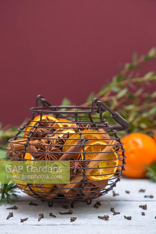 A scented wire basket containing Star anise, dried Citrus fruit and Cinnamon sticks