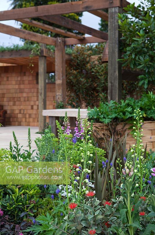 Raised garden bed looking towards recycled timber pergola, cedar shingle clad walled dining area.