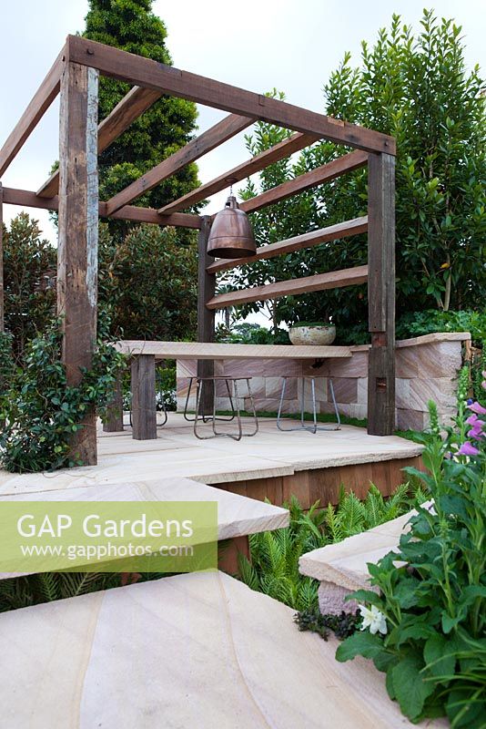 Recycled timber pergola and sandstone outdoor dining table showing suspended sandstone steps.
