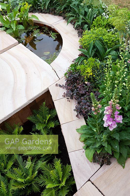 Sunken sandstone garden bed with curved edges and a semi-circular water feature.