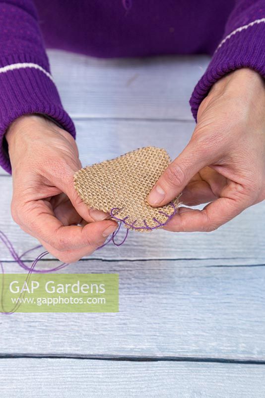 Use a needle and the purple string to sew the two hessian hearts together to form a satchel