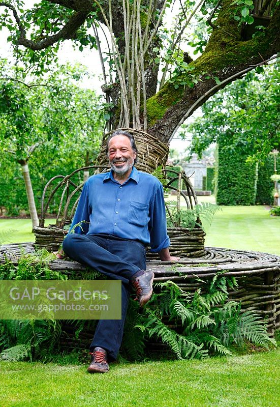 Patrice Taravella sits on a willow seat surrounding an old pear tree in the orchard in the Prieuré Notre-Dame d'Orsan.