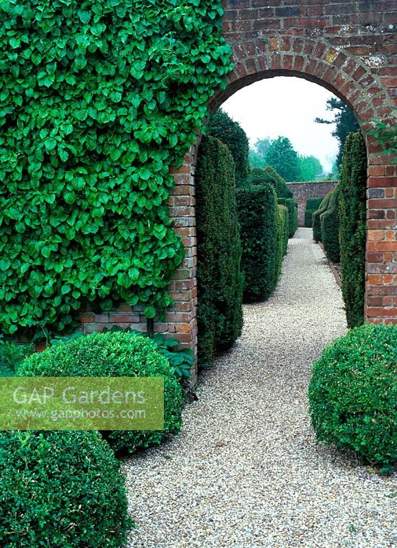 Archway in brick wall, view to topiary garden. Godmersham Park. Owner: John Sunley