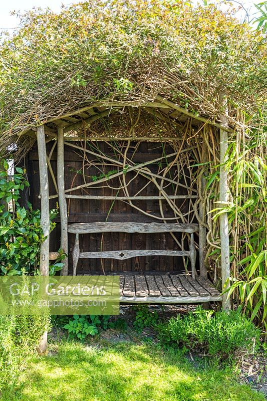 Handmade arbour with built in seat festooned  with Jasminum officinale.