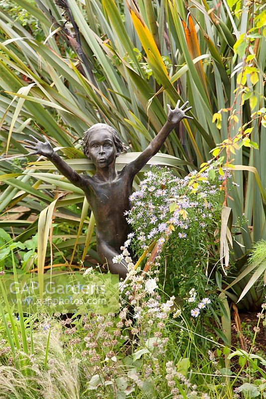Walled garden, Cambo, Fife, Scotland, UK. Bronze statue by Asters and phormium