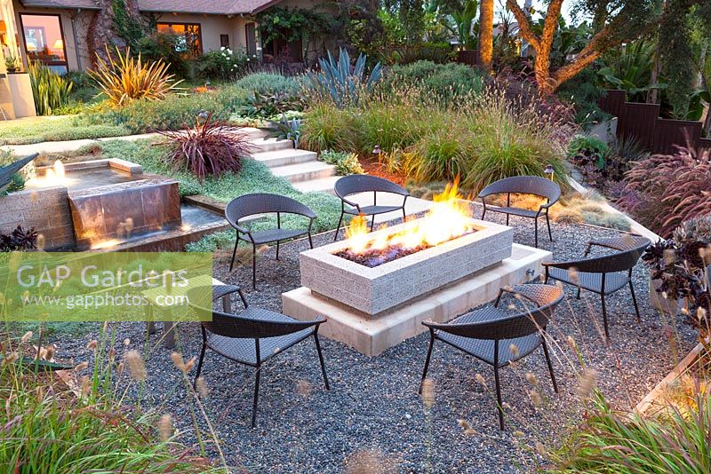 View of fire pit alight and outside seating area at night. Debora Carl's garden, Encinitas, California, USA. August.