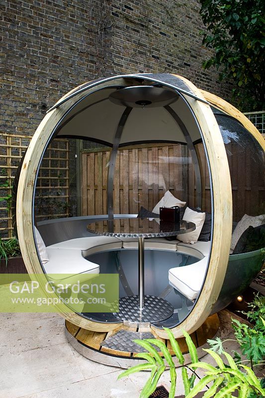 Large round wooden and perspex pod with seating and a table. Outdoor room