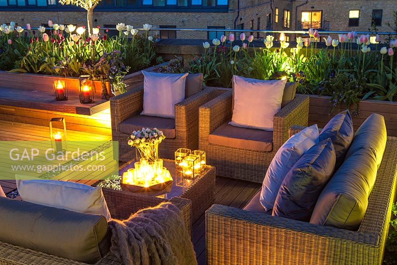 Outside seating area on a London roof terrace at night with candles and outside lighting.  April. 