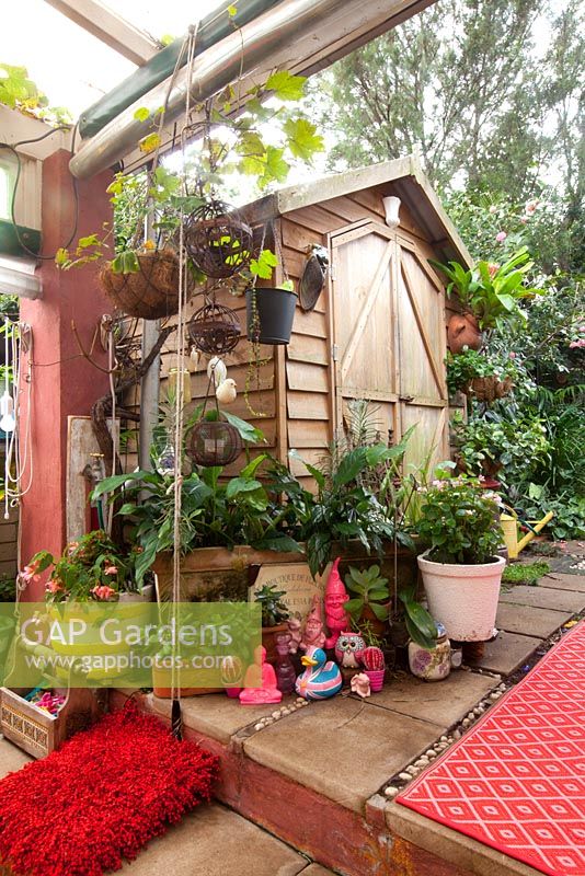 A collection of quirky pink coloured decorative objects in front of a small timber garden shed.