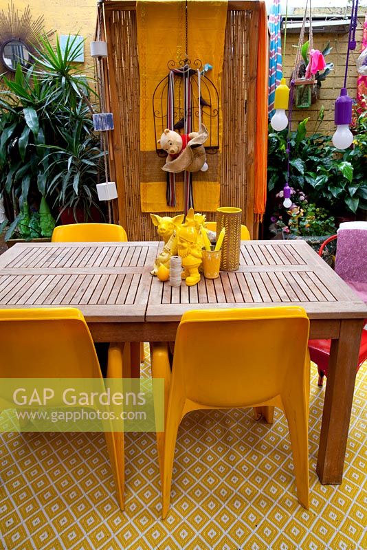 Inner city garden with begonias and spathiphyllums features colourful eclectic retro pieces sourced from local markets, including a timber dining setting with assorted yellow objects
