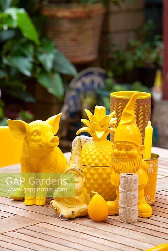 A collection of quirky yellow statues, including a pig, a pineapple and two garden Gnomes
