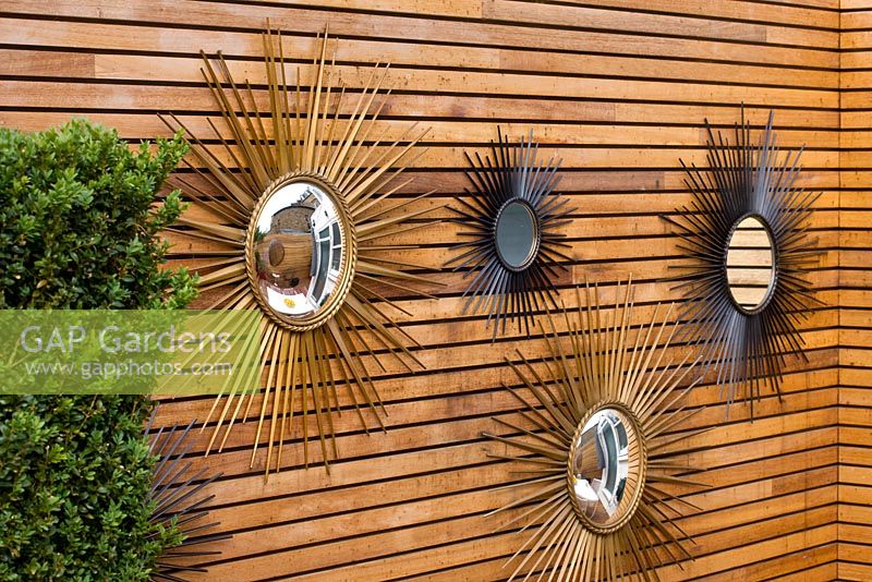French sixties sunburst mirrors on wall in the garden. Ben De Lisi House and Garden, London