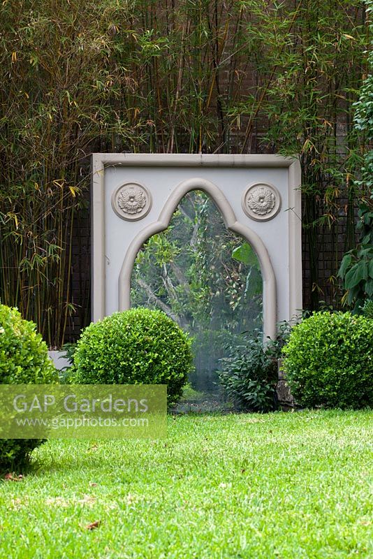 Large freestanding Gothic style cast cement frame with a mirror in front of a green screen.
