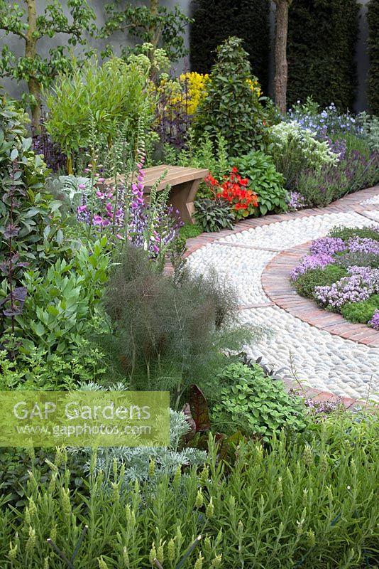 The St John's Hospice - A Modern Apothecary,  peaceful seating area with cobbled path, surrounded by herbs, including bay, fennel, lavender and sage - Designer: Jekka McVicar - RHS Chelsea Flower Show, 2016.