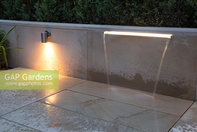 Water feature built into sandstone patio wall with the addition of downlight lighting