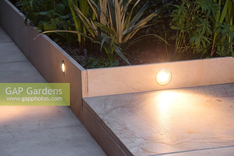 Lighting integrated into sandstone patio, illuminating steps leading to garden