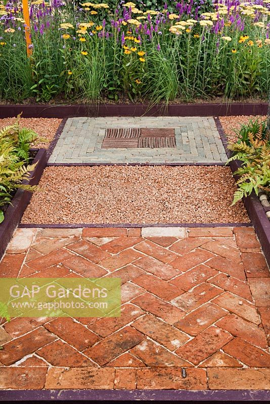 Mixed hard surfaces, brick paving in a herringbone design and painted wooden edges to beds. Garden: 'Nature Squared' at RHS Tatton Park Flower Show 2012