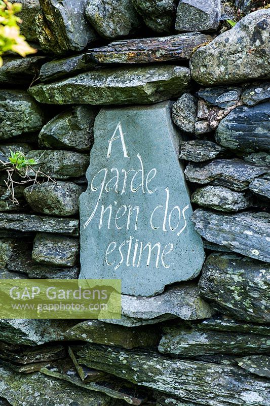 A slate set into a garden wall reads 'A garden encloses time'.