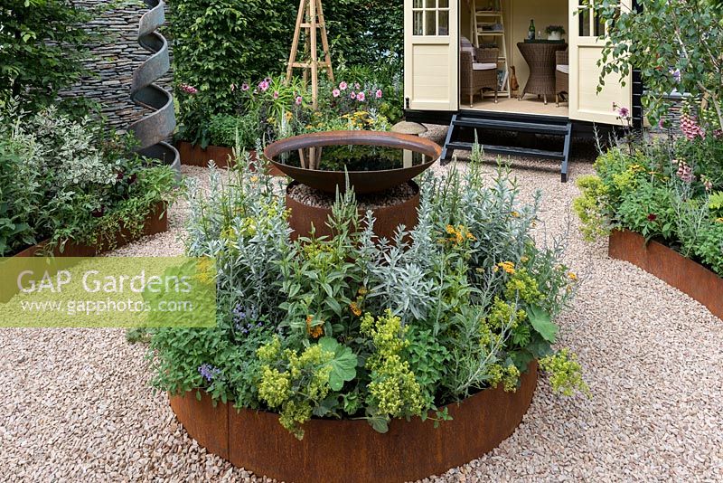 An Arts and Crafts inspired garden with a circular theme, raised corten steel borders, water feature and summerhouse. A Summer Retreat designed by Laura Arison and Amanda Waring. RHS Hampton Court Flower Show 2016