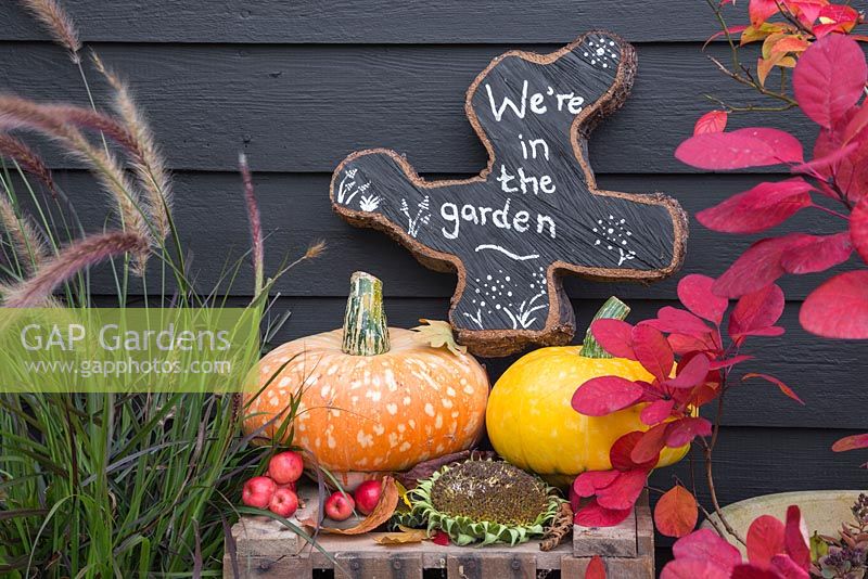 Oak tree slice painted and decorated to display 'We're in the garden' with Autumnal display