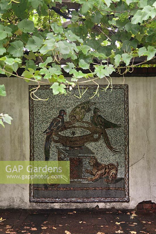 Tile wall mosaic of birds and animals under grapevine