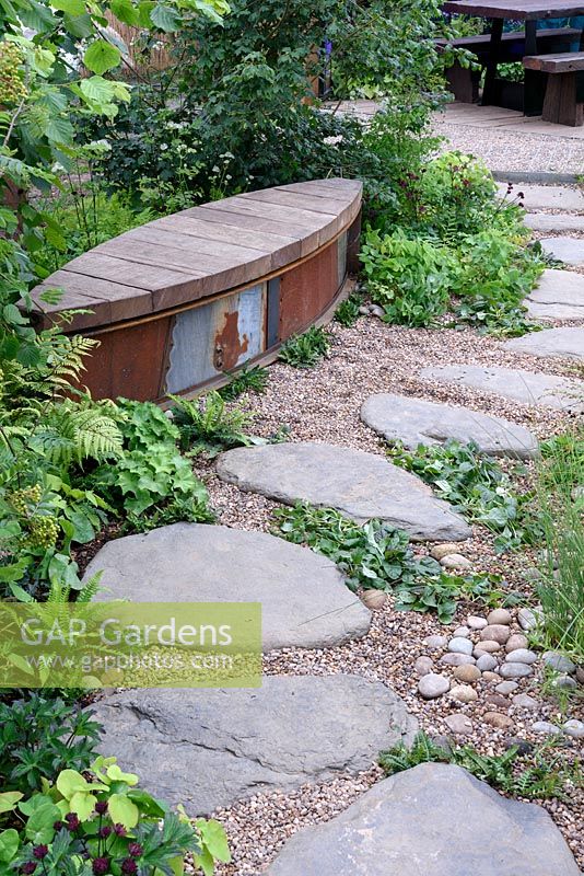 The WWT Working Wetlands Garden. Unusual garden bench along stepping stone path. Designer: Jeni Cairns, Sponsors: WWT. RHS Hampton Court Palace Flower Show 2016