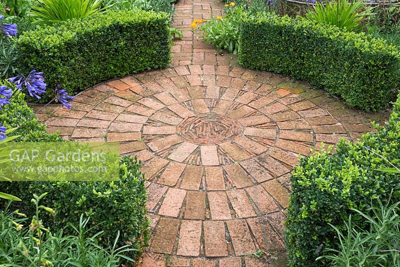 Circular brick paving surrounded by curved Buxus sempervirens hedges