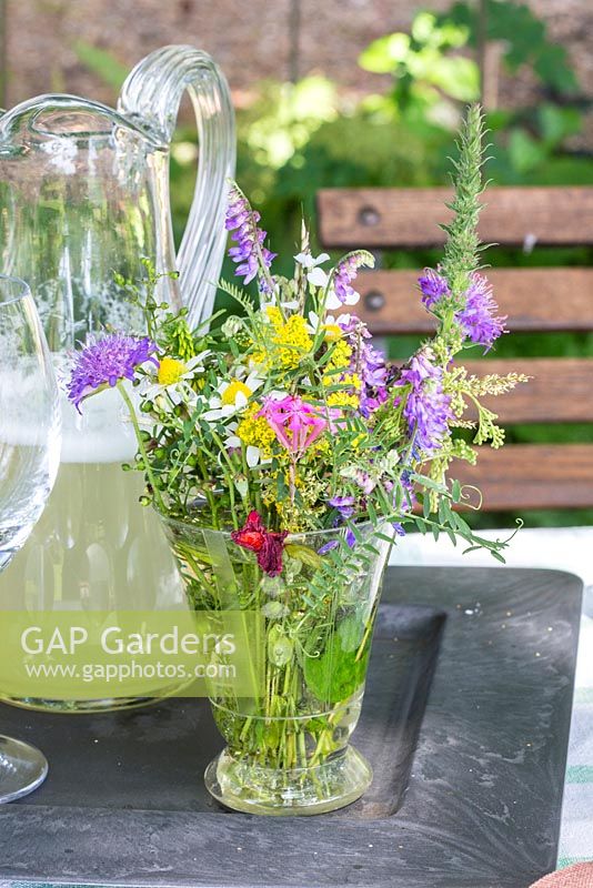 Bunch of wildflowers and glass jug with homemade lemonade and on a tray, Galium, Knautia arvensis, Leucanthemum vulgare, Silene armeria, Vicia cracca